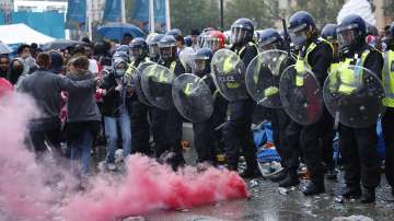 People run away as a smoke flare is set off in front of a police line near Leicester Square in London, Sunday, July 11