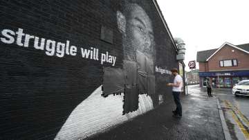 Ed Wellard, from Withington, tapes bin liners across offensive wording on the mural of Manchester United striker and England player Marcus Rashford on the wall of the Coffee House Cafe on Copson Street, which appeared vandalised