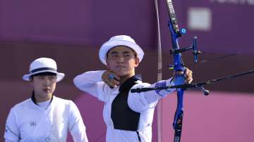 South Korea's Kim Je Deok releases an arrow flanked by his teammate An San during the mixed team competition at the 2020 Summer Olympics, Saturday, July 24