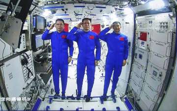In this photo released by China's Xinhua News Agency, Chinese astronauts, from left; Tang Hongbo, Nie Haisheng, and Liu Boming salute from aboard China's space station core module Tianhe during a video conversation with Chinese President Xi Jinping.
