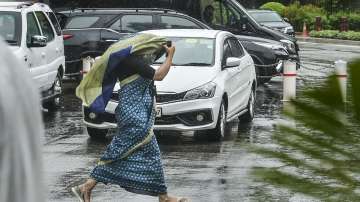 A parliamentary staff looks for cover as it rains in Delhi.