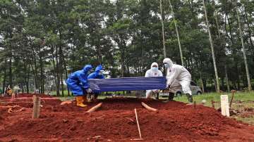 Workers in protective suits prepare to lower a coffin containing the body of a COVID-19 victim into a grave at Cipenjo cemetery in Bogor, West Java, Indonesia, Wednesday, July 14, 2021. 