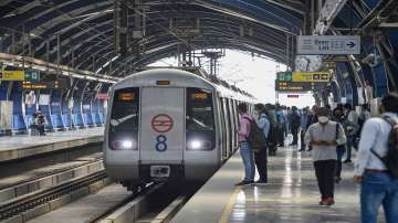 Commuters wait to board a train after resumption of the Delhi Metro services.