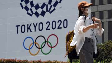 In this Tuesday, July 20, 2021, file photo, a woman wearing a protective mask walks in front of a Tokyo 2020 Summer Olympics display at the Tokyo Metropolitan government in Tokyo.