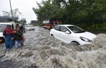 Commuters wade through a waterlogged street due to heavy rains, at Ring Road in New Delhi, Monday, July 19, 2021.