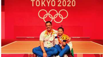 Indian Weightlifter Saikhom Mirabai Chanu with her coach Vijay Sharma, poses after winning silver medal in womens 49 kg category weightlifting event at the Summer Olympics 2020, in Tokyo