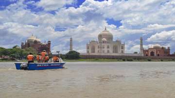 Police personnel patrol at the swollen Yamuna River in the backdrop of the Taj Mahal in Agra, Saturday, July 31