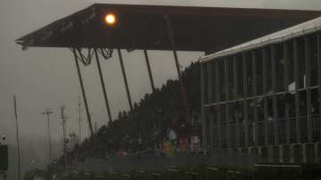 Spectators wait under an overhang during a rain delay at the Formula One Grand Prix at the Spa-Francorchamps racetrack in Spa, Belgium, Sunday, Aug. 29