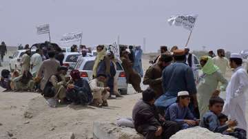 People with the Taliban's signature white flags wait for the arrival of their relative, who was released from prison by the Taliban in Afghanistan, at a border crossing point, in Chaman, Pakistan, Tuesday, Aug. 17, 2021.