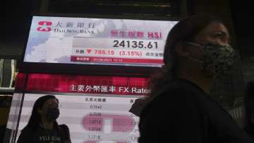 People walk past a bank's electronic board showing the Hong Kong share index at Hong Kong Stock Exchange in Hong Kong Monday.