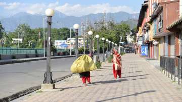Workers walk on a pavement during lockdown imposed in Jammu and Kashmir administration to contain the surge in COVID-19 cases.