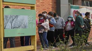 Residents wearing face masks to help curb the spread of the coronavirus line up to receive booster shots against COVID-19 at a vaccination site displaying a poster baring the words: "Epidemic protection" in Beijing
 