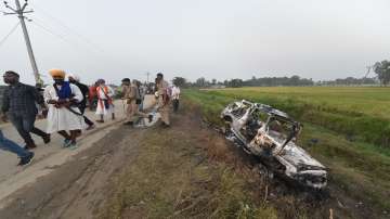 People take a look at the overturned SUV which destroyed in yesterdays violence during farmers protest, at Tikonia area of Lakhimpur Kheri district, Monday.