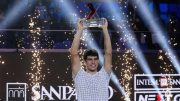 Spain's Carlos Alcaraz holds a trophy after winning the ATP Next Gen final tennis tournament against