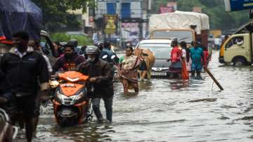 Commuters wade through a waterlogged area following heavy rain, in Chennai on Wednesday.