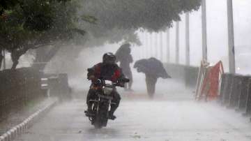 A man rides a bike during heavy rain near Marina Beach, in Chennai.