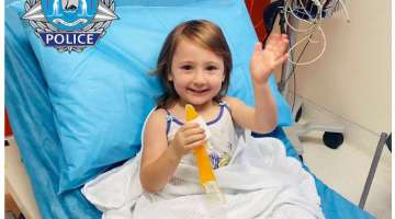 In this photo provided by the Western Australia Police, four-year-old Cleo Smith waves as she sits on a bed in hospital