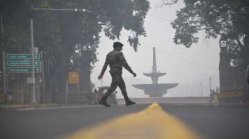 A security personnel crosses a road near the Rashtrapati Bhavan, shrouded in smog, in New Delhi.