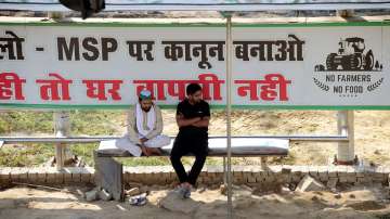 Two persons sit at a bus stop at the Ghazipur border as barricades are removed from the farmers protest site.