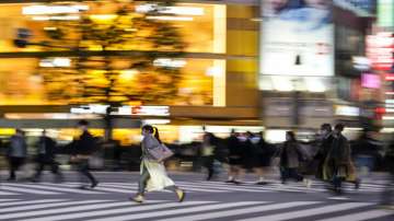 People wearing protective masks walk around the famed Shibuya scramble crossing in a shopping and entertainment district.