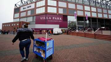 A programme seller takes her stall back towards the stadium following the news that Aston Villa's ma