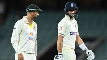 Nathan Lyon of Australia and Joe Root of England share a laugh as they walk off the field due to lig