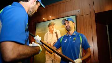 Glenn Maxwell and Nathan Lyon hold one of Sir Donald Bradman's bats during an Australian cricket squ