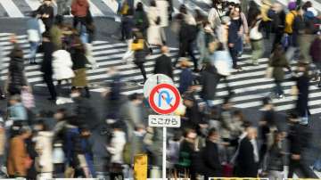 People wearing face masks walk along a pedestrian crossing at Shibuya district in Tokyo.?