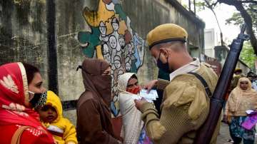 A security person checks ID cards of voters outside a polling booth during Kolkata Municipal Corporation elections, in Kolkata.