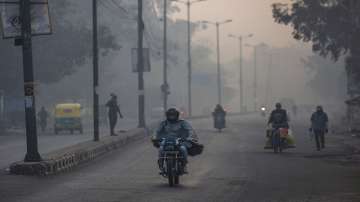 A man wrapped in a shawl rides a motorbike on a cold morning in New Delhi.