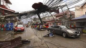 Cars pass by a toppled electrical post due to Typhoon Rai in Surigao city, Surigao del Norte, southern Philippines as power supply remain down.