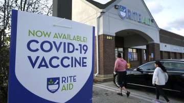 People walk past a COVID-19 vaccine sign as they enter a Rite Aid pharmacy, in Nashua, N.H.?