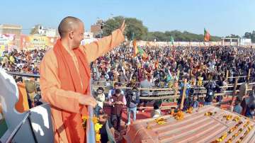 Uttar Pradesh Chief Minister Yogi Adityanath waves towards supporters during the inauguration of BJPs Jan Vishwas Yatra ahead of the 2022 UP elections.