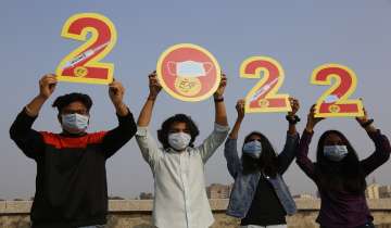 Indians, wearing face masks to help curb the spread of the coronavirus, hold the cutouts to welcome 2022 on New Year's Eve in Ahmedabad.