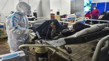 A health worker interacts with a Covid-19 infected patient resting on her bed inside a Covid care centre of the Commonwealth Games (CWG) village, in New Delhi