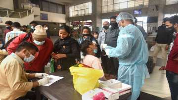 A healthcare worker collects swab sample of passengers for Covid-19 test, at Bandra Terminus, in Mumbai