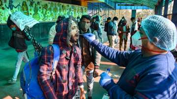 A health worker takes swab sample of a passenger for COVID-19 test at New Delhi Railway station amid concern over rising Omicron cases, in New Delhi.