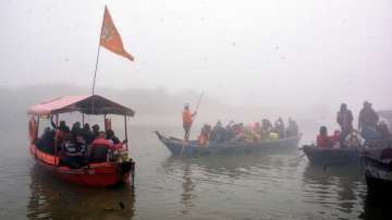 Devotees ride on boats on the Ganga river during the Makar Sankranti festival, as a thick layer of fog shrouds the Sarsaiya Ghat in Kanpur, Friday, Jan. 14, 2022.