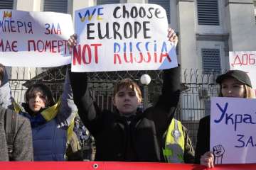 Protesters hold posters in front of the Russian Embassy in Kyiv, Ukraine