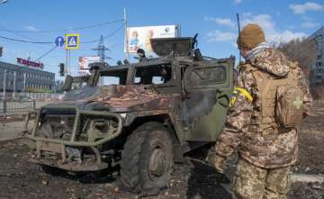 A Ukrainian soldier inspects a damaged military vehicle after fighting in Kharkiv