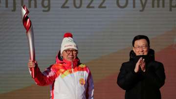 First Torch bearer Luo Zhihuan holds up the torch after receiving it from Chinese Vice Premier Zheng