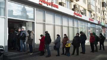 People stand in line to withdraw money from an ATM of Alfa Bank in Moscow, Russia