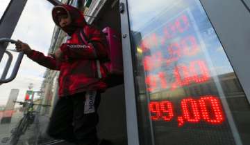 A food delivery man leaves an exchange office with screen showing the currency exchange rates of U.S. Dollar and Euro to Russian Rubles in Moscow,