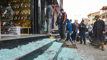 People gather near shops damaged in a grenade attack by militants, at Khwaja Bazar area in Srinagar, Friday, Feb. 18, 2022.
