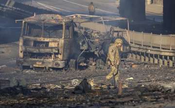 A Ukrainian soldier walks past debris of a burning military truck, on a street in Kyiv, Ukraine