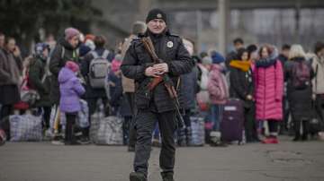 A Ukrainian policeman walks on a platform backdropped by people waiting for a Kiev bound train in Kostiantynivka, the Donetsk region, eastern Ukraine, Thursday, Feb. 24, 2022.