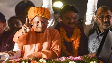 UP Chief Minister Yogi Adityanath flashes the victory sign during a roadshow, in support of BJP candidate Rajeshwar Singh for UP Assembly elections, in Lucknow.