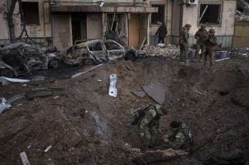 A Ukrainian bomb squad inspect the site of an explosion after bombing in Kyiv, Ukraine, Sunday, March 20, 2022. 