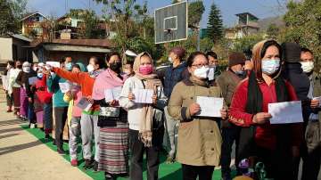 Voters holding their identification cards stand in a queue to cast their votes for the second phase of Manipur Assembly elections, in Senapati. 