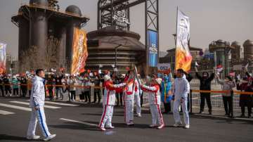 Torch bearers pass the flame to each other during the Beijing 2022 Paralympic torch relay.